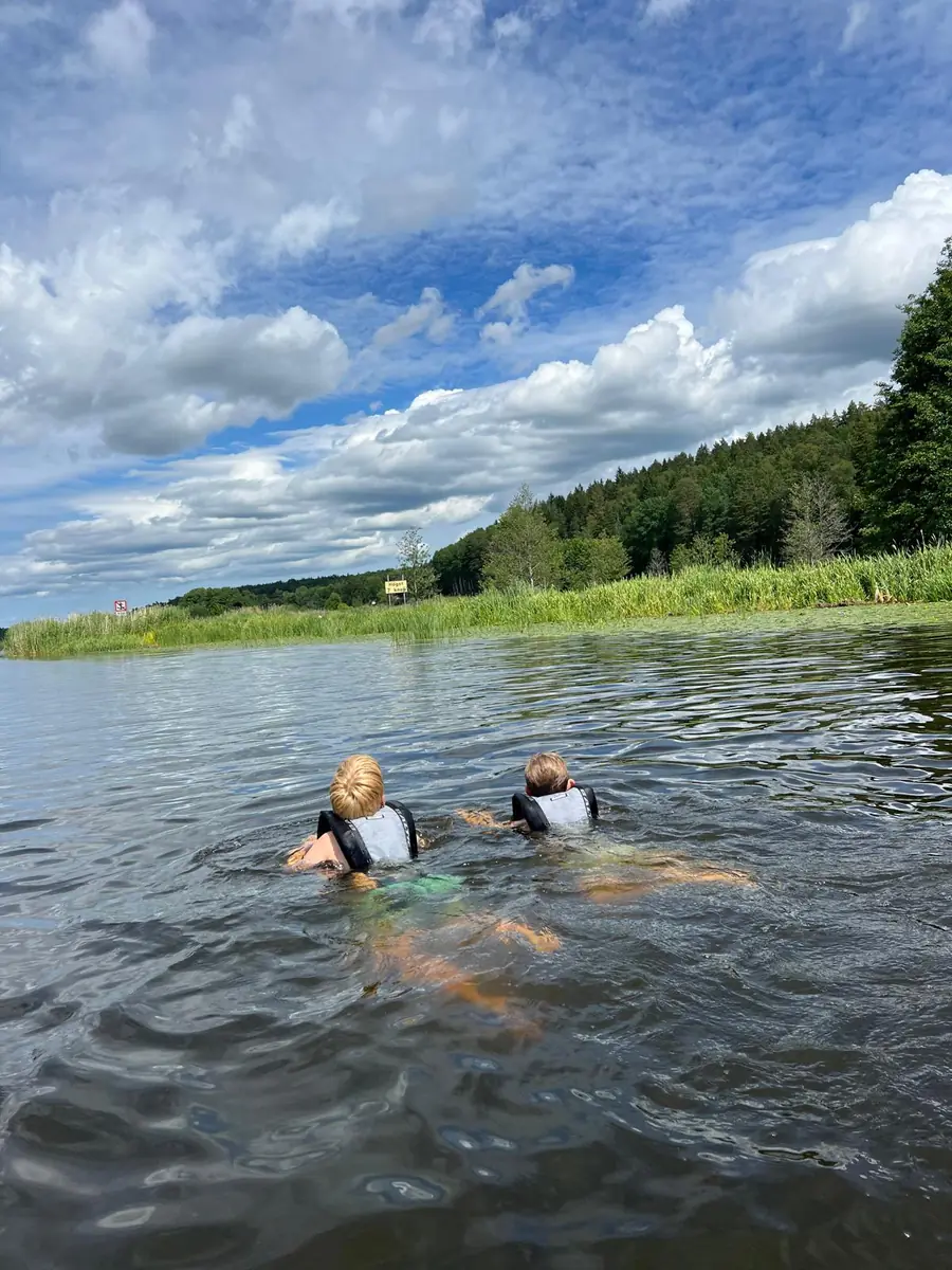 Två barn simmar i flytväst under sommarlägret