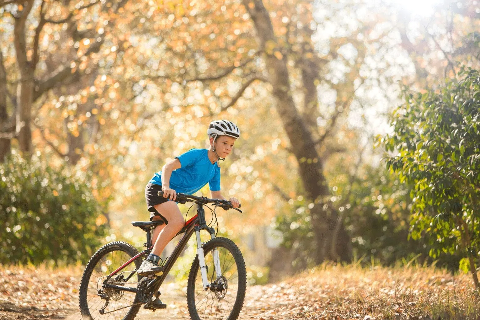 Barn med hjälm på en mountainbike i skogen