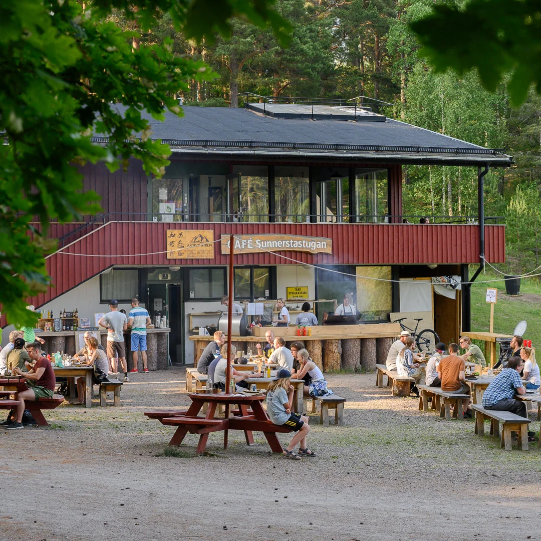 Gäster vid borden framför Sunnerstastugan på sommaren